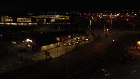 Night-flying-orbit-McDonalds-fast-food-drive-through-in-Northern-UK-town-aerial-view