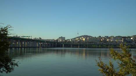 Ultrawide-view-of-Han-river,-Yongsan-district-with-N-Seoul-Tower-on-Namsan-mountain-and-Hannam-bridge,-Autumn-foliage-on-cloudless-day,-South-Korea-static