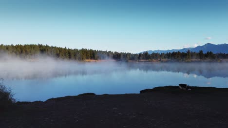 Lake-with-mist-approached-from-shore-with-fire-pit-dolly-Enid-British-Columbia-Canada