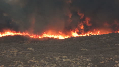 A-shot-of-the-raging-flames-and-smoke-of-a-devastating-wildfire-sweeping-across-the-mountainous-landscape-of-Hemet,-California