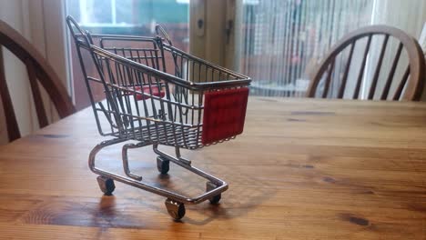 Mini-empty-shopping-trolley-online-home-delivery-concept-on-kitchen-table-orbit-right
