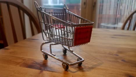 Mini-empty-shopping-trolley-online-home-delivery-concept-on-kitchen-table-pull-back-to-wide-reveal