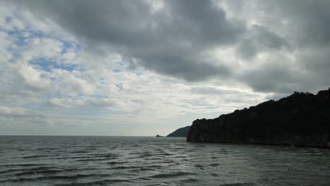 Luftaufnahmen,-Die-Nach-Rechts-über-Das-Meer-Gleiten,-Zeigen-Inseln-Am-Horizont-Und-Einen-Berg,-Der-Eine-Silhouette-Bildet,-Graue-Wolken