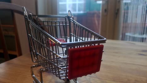 Mini-empty-shopping-trolley-online-home-delivery-concept-on-kitchen-table-pull-back-shallow-focus-to-blur