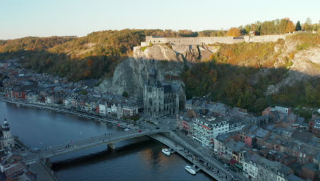 Aerial-View-Of-Dinant-City-Along-River-Meuse-With-Catholic-Church-And-Fortress-On-Cliffs-In-Belgium