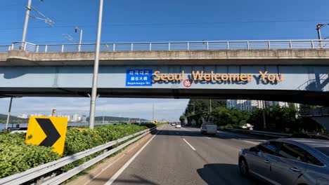 Driver's-POV-driving-on-Olympic-daero-highway-passing-Seoul-Welcomes-You-sign-on-Magok-bridge
