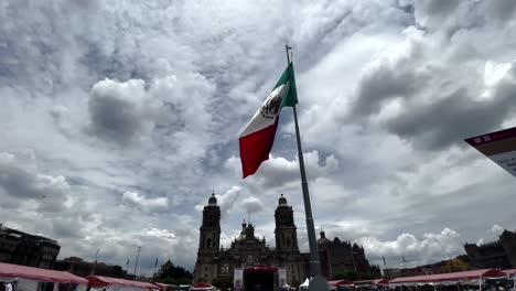 Aufnahme-Der-Mexikanischen-Flagge,-Die-Bei-Sonnenuntergang-Vor-Der-Metropolitankathedrale-Mit-Voller-Sicht-Auf-Den-Zocalo-Im-Hintergrund-Weht