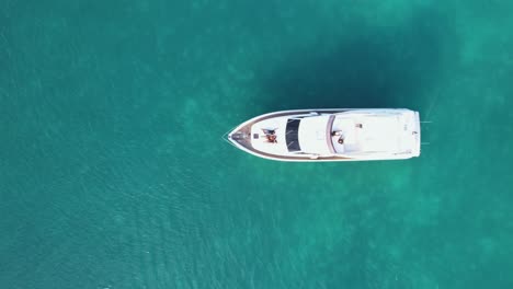 Aerial-view-above-people-chilling-on-a-yachts-deck-in-middle-shallow,-turquoise-caribbean-sea---top-down,-drone-shot