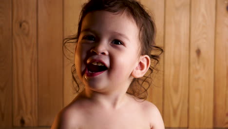 Junges-Kleinkind-Liest-Und-Lächelt-In-Die-Kamera-Und-Schaut-Sich-Auf-Holzhintergrund-Mit-Gelber-Randbeleuchtung-Um