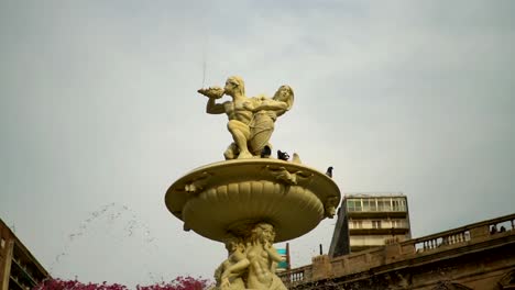 Slow-motion,-handheld-low-angle-view-of-a-dove-landing-on-the-Utopias-Fountain-in-Rosario,-Argentina