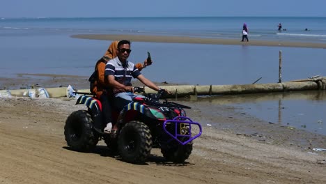 central-java,-Indonesia--September-2,-2022:-visitors-ride-ATV-on-beach,-slowmo