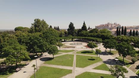 Vista-Aérea-Hacia-Atrás-Del-Elegante-Jardín-Público-Con-Fuente