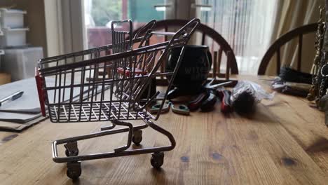 Small-shopping-trolley-online-home-business-concept-on-kitchen-table-copy-space-closeup-tracking-left-shot