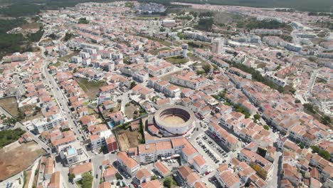 Aerial-tilt-up-over-bullring-surrounded-by-residential-Houses-reveal-Nazaré-Cityscape