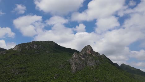 Un-Metraje-Constante-De-Esta-Roca-En-Una-Montaña-De-Piedra-Caliza-Con-Nubes-Esponjosas-Y-Cielo-Azul