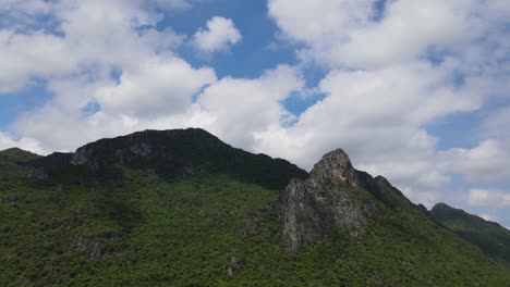 Sliding-aerial-footage-towards-the-left-revealing-this-majestic-limestone-mountain,-lovely-cotton-like-clouds,-blue-sky
