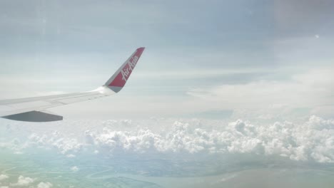 Blick-Auf-Den-Airaisa-Airbus-A320-Flugzeugflügel-Durch-Das-Flugzeugfenster,-Das-über-Die-Wolke-Fliegt