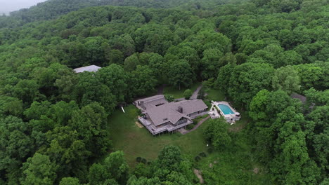 4K-Aerial-orbiting-large-house-in-lush-green-forest-with-pool,-Real-Estate