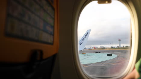Flugzeug,-Das-Vom-Flughafen-Lissabon-Abhebt,-Mit-Dem-Ryanair-Logo-Auf-Dem-Flugzeugflügel,-Das-Durch-Das-Fenster-Gesehen-Wird---POV