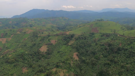 Misty-flight-over-patchwork-of-crop-fields-on-steep-jungle-hillsides