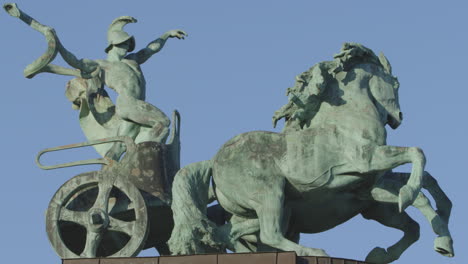 Vista-Lateral-De-La-Antigua-Estatua-De-Un-Hombre-En-Un-Carro-Como-Símbolo-De-Guerra-Y-Victoria