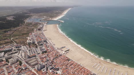 Long-white-sand-beach-and-resort-town-of-Nazare,-Portugal