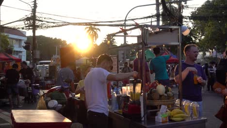 Foreigners-buying-juice-at-street-market-vendor-stall-in-Thailand