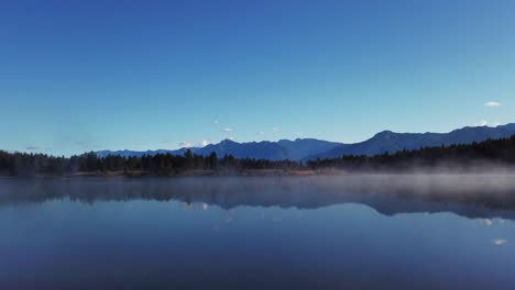 Lake-mist-with-mountains-and-forest-pan-Enid-British-Columbia-Canada