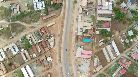 Top-down-aerial-of-traffic-on-a-calm-road-running-through-a-small-town-in-Kenya