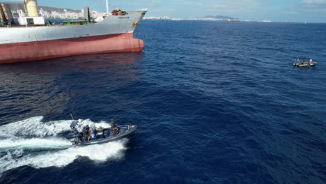 Aerial-shot-of-a-speedboat-of-the-national-police-passing-near-a-merchant-ship