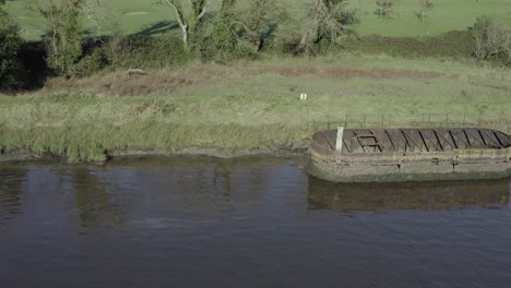 Rusting-steel-remains-of-river-barge-on-riverbank-near-golf-course