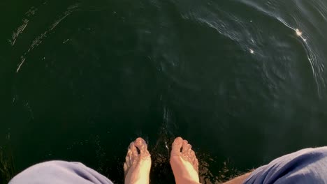 First-person-perspective-view-of-relaxing-feet-on-the-lake-water