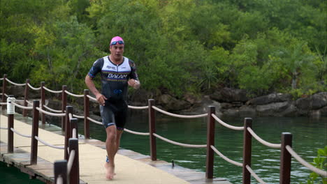 Athlete-running-in-slow-motion-crossing-a-bridge-after-finishing-the-swimming-stage-of-a-triathlon