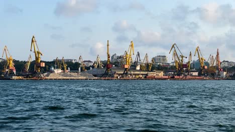 Doppelauslegerkräne-Im-Hafen-Von-Odessa-Mit-Sandhaufen-Von-Einem-Boot,-Das-Am-Schwarzen-Meer-Segelt
