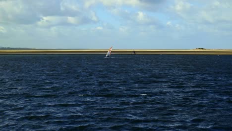 Lone-water-sports-windsurfer-in-slow-motion-sails-on-a-choppy-marine-lake-at-West-Kirby
