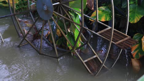 4K-Waterwheel-Spinning-Slowly-Close-up-with-Wooden-Paddles-and-Metal-Frame-in-Murky-Water
