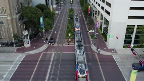 Aerial-view-following-a-tram-on-the-Main-street,-evening-in-Houston,-Texas,-USA
