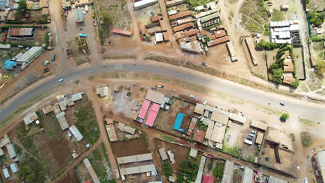 Vista-De-Arriba-Hacia-Abajo-Del-Tráfico-En-Un-Camino-Tranquilo-Que-Atraviesa-Un-Pequeño-Pueblo-En-Kenia