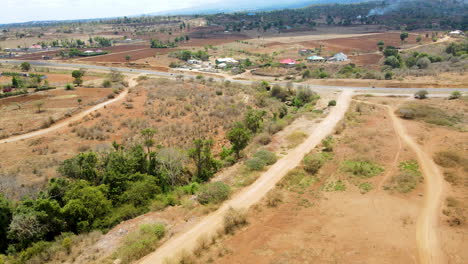 Jib-down-of-a-dirt-road-running-towards-an-asphalt-road-in-Rural-Kenya
