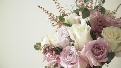 Aufsteigender-Schuss-In-Zeitlupe-Eines-Hochzeitsstraußes-Mit-Verschiedenen-Blumen-Mit-Rosa-Und-Gelben-Rosen,-Dekorationen-Und-Schleifen-Vor-Weißem-Hintergrund