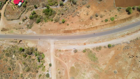 Top-down-aerial-of-motorbike-driving-over-road-in-rural-Kenya