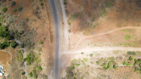 Top-down-aerial-of-a-road-running-through-a-dry-and-barren-landscape-in-rural-Kenya