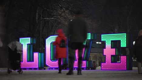 People-admiring-a-large-glowing-love-sign