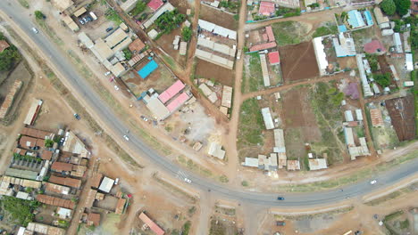 Top-down-view-of-cars-and-motorbikes-on-a-calm-road-running-through-a-small-town-in-Kenya