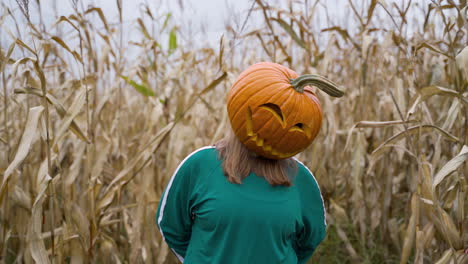 Film-Noir-Woman-In-Pumpkin-Head-Standing-In-Corn-Field