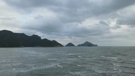 Luftaufnahmen-Zu-Diesen-Inseln-Und-Bergen,-Die-Wellen-Und-Den-Dunklen-Morgenhimmel-Mit-Regenwolken-Zeigen