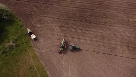 Aerial-top-down-of-farmers-fixing-industrial-machinery-and-tractor-an-agriculture-farm
