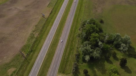 Aerial-flyover-rural-road-with-a-few-cars-traveling-during-sunny-day---4K-Drone-top-down-shot
