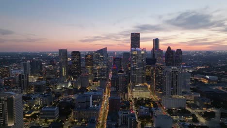 Aerial-view-around-the-illuminated-Houston-skyline,-colorful-dusk-in-Texas,-USA---circling,-drone-shot
