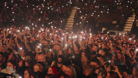 Calm-Quiet-Spectators-Crowd-Looking-at-Stage-Holding-Luminous-Phones-and-Lights-During-Music-Concert-Show,-Stands-and-Audience-Fans-in-Arena